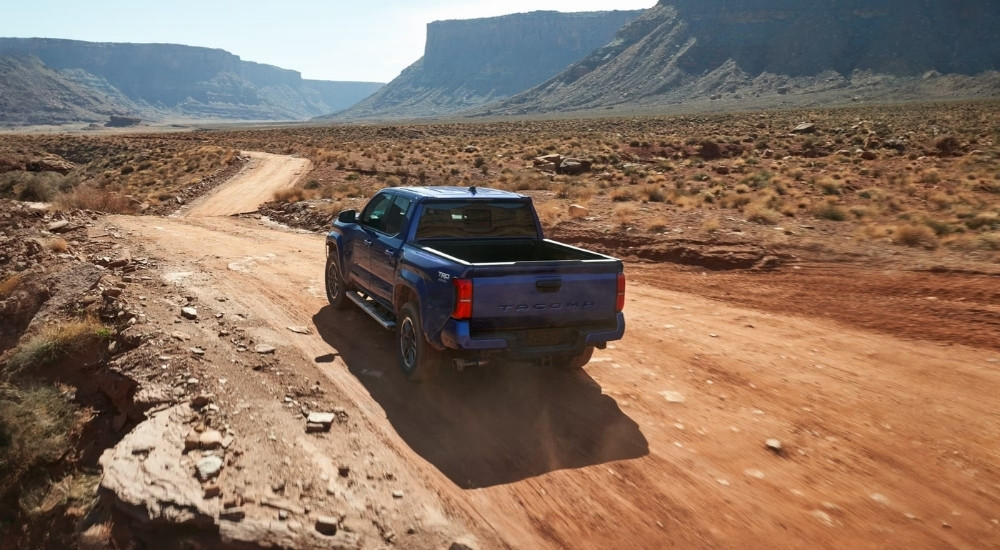 A blue 2024 Toyota Tacoma TRD Sport driving to a Toyota dealer.