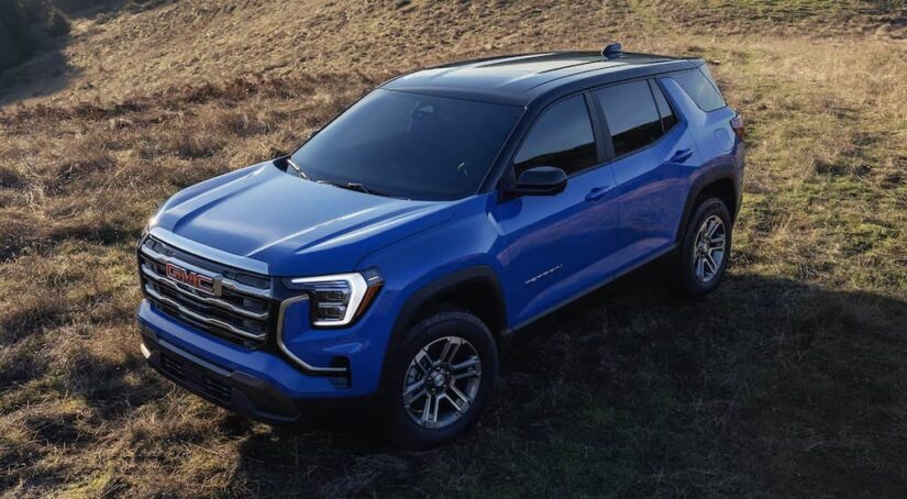 A blue 2025 GMC Terrain parked off-road in grass