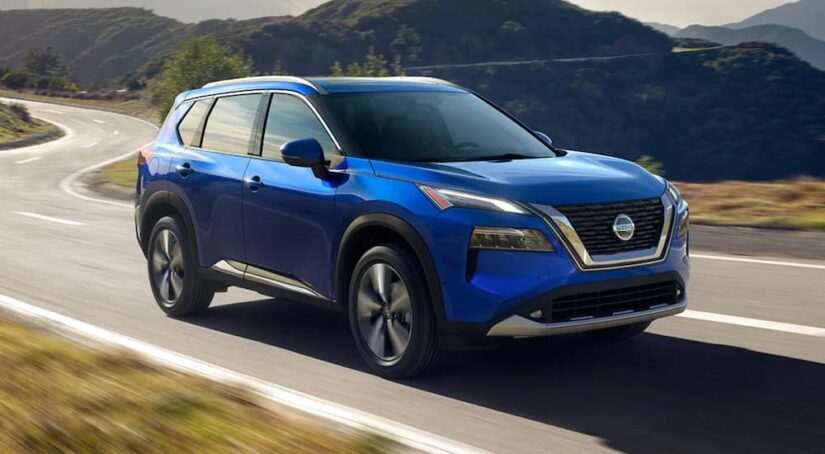 A blue 2021 Nissan Rogue driving down a highway