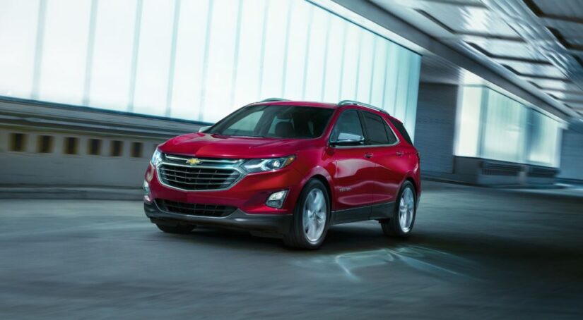 A red 2019 Chevy Equinox driving to look at used cars for sale.