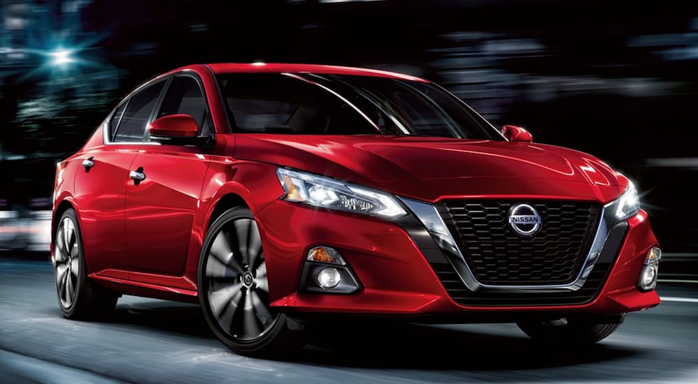 A red 2021 Nissan Altima driving on a city street.