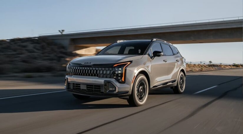 A gray 2026 Kia Sportage driving near an overpass.
