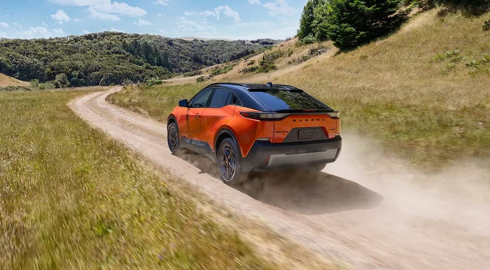An orange 2026 Subaru Uncharted driving on a dirt road.