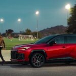 A red 2026 Toyota RAV4 parked near a soccer field.