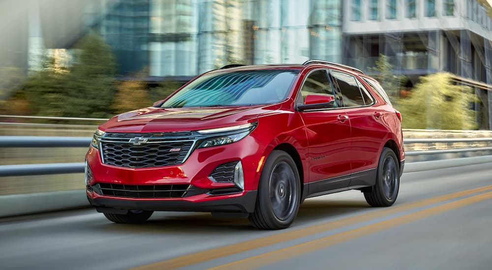 A red 2022 Chevy Equinox RS driving in a city.