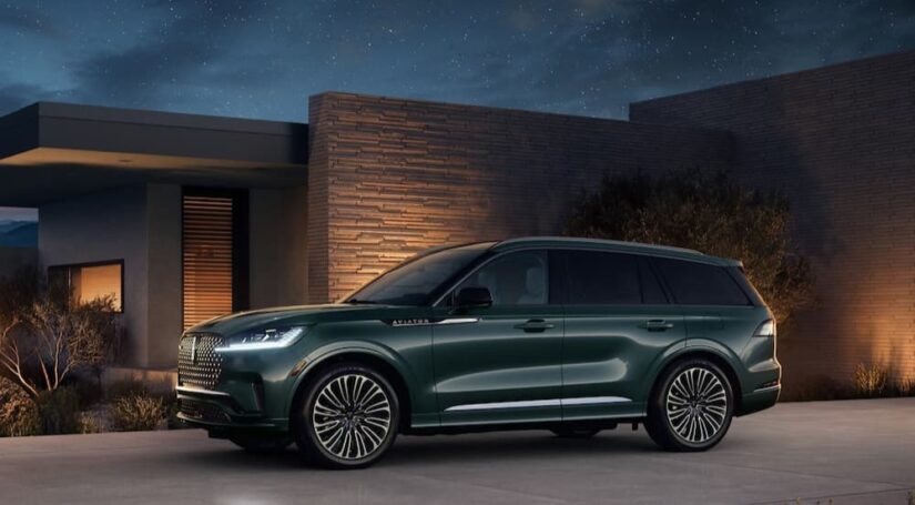 A green 2025 Lincoln Aviator parked near a house at night.