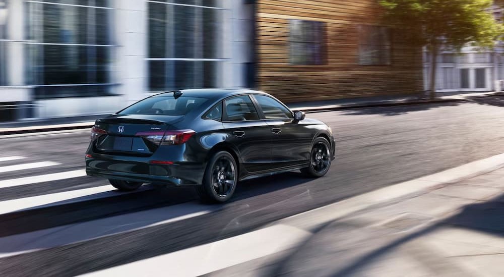 A black 2026 Honda Civic Sport Hybrid driving in a city.