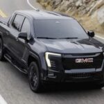 A black 2026 Sierra EV driving down a highway