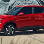 A red 2025 Hyundai Venue parked near a Hyundai dealer.