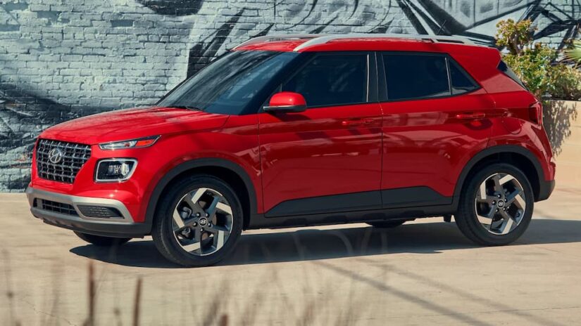 A red 2025 Hyundai Venue parked near a Hyundai dealer.