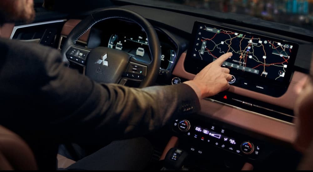 A person touching the infotainment screen in a 2025 Mitsubishi Outlander.
