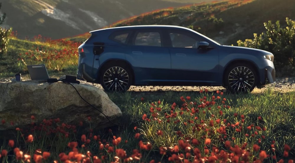 A blue 2026 BMW iX3 parked near flowers.