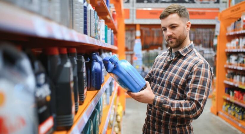 A person holding a container of engine oil.