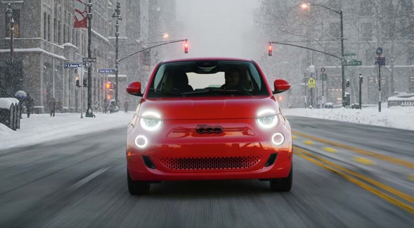 A red FIAT 500e driving on a snowy day.