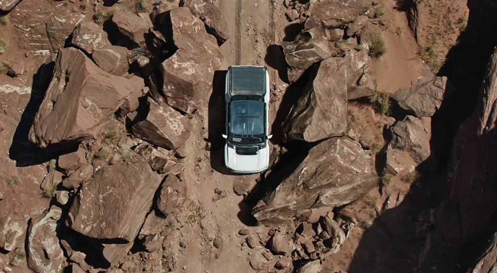 White 2025 GMC Hummer EV driving on a trail