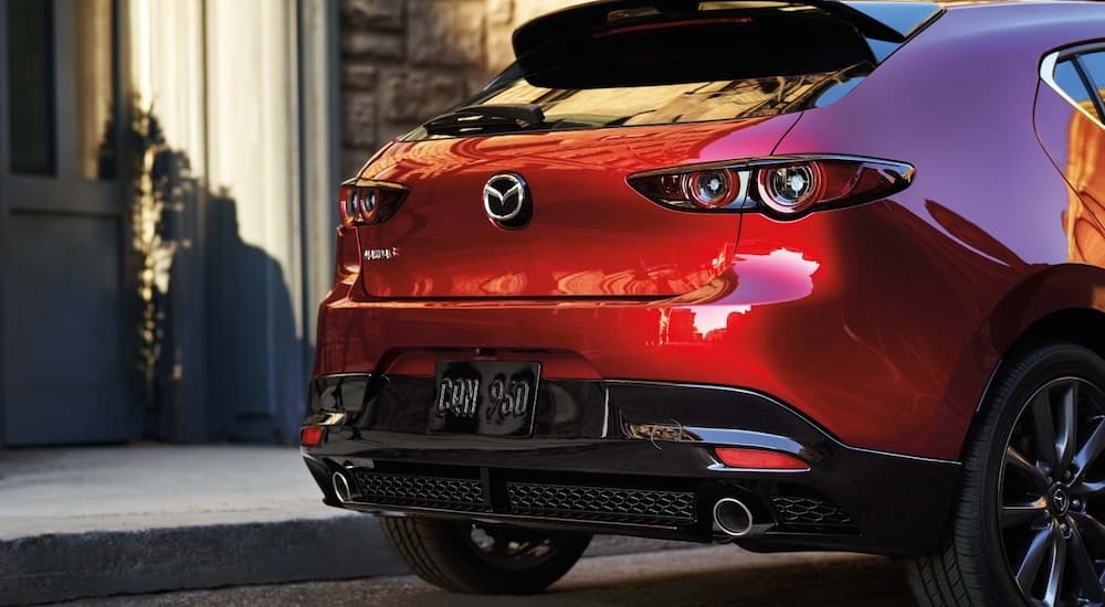 Rear view of a 2026 Mazda3 from an angle parked along a curb.