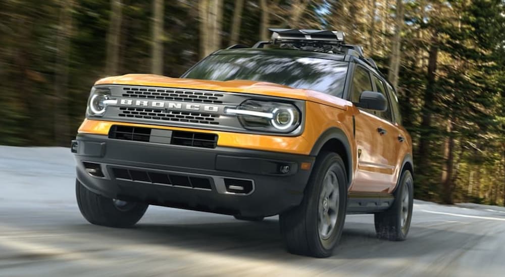 Yellow 2025 Ford Bronco Sport for sale driving down a city road.