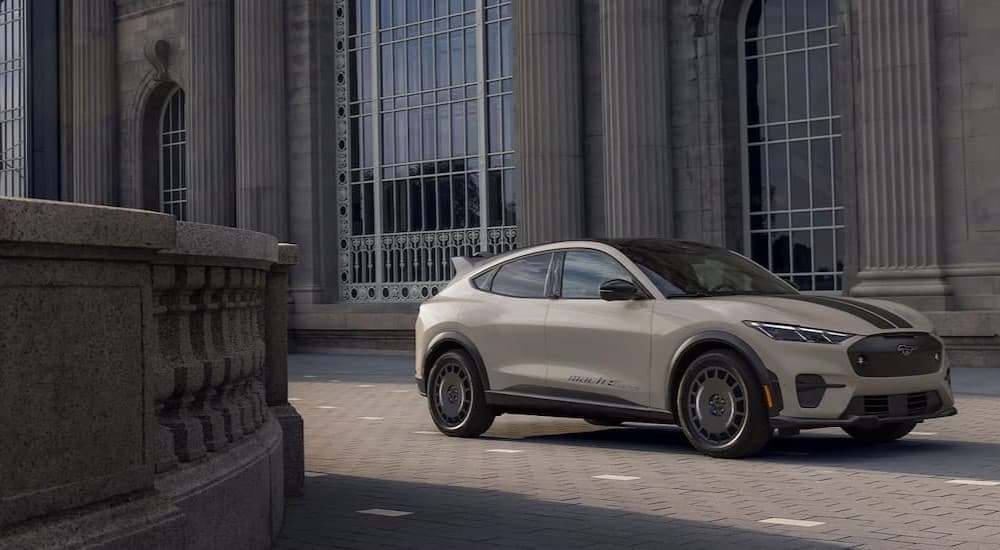 A tan 2025 Ford Mustang Mach-E parked near a building.