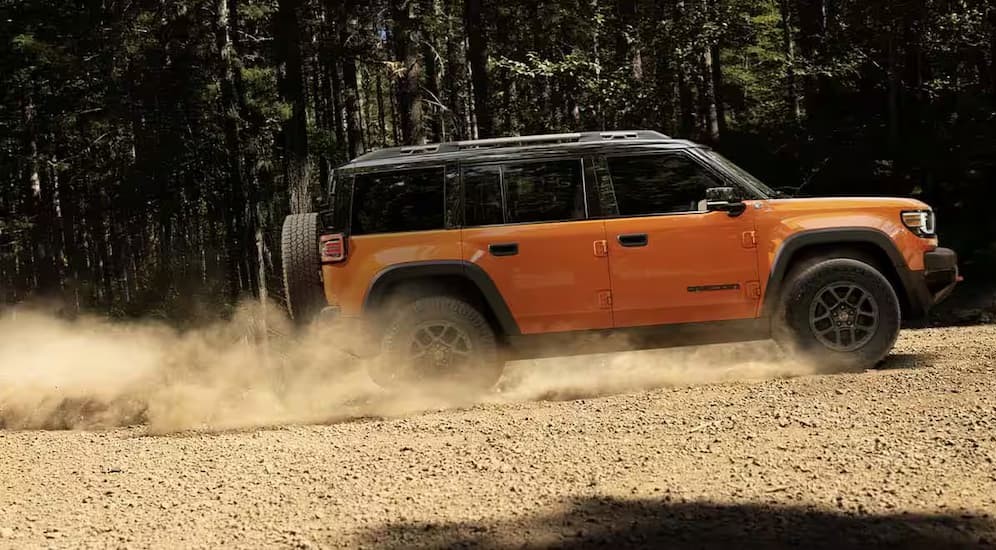 An orange 2026 Jeep Recon driving uphill.