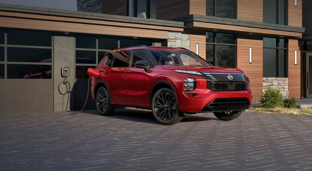 Red 2026 Nissan Rogue PHEV charging on a driveway