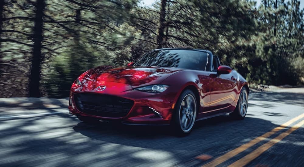 A red 2021 Mazda MX-5 Miata driving on a highway.