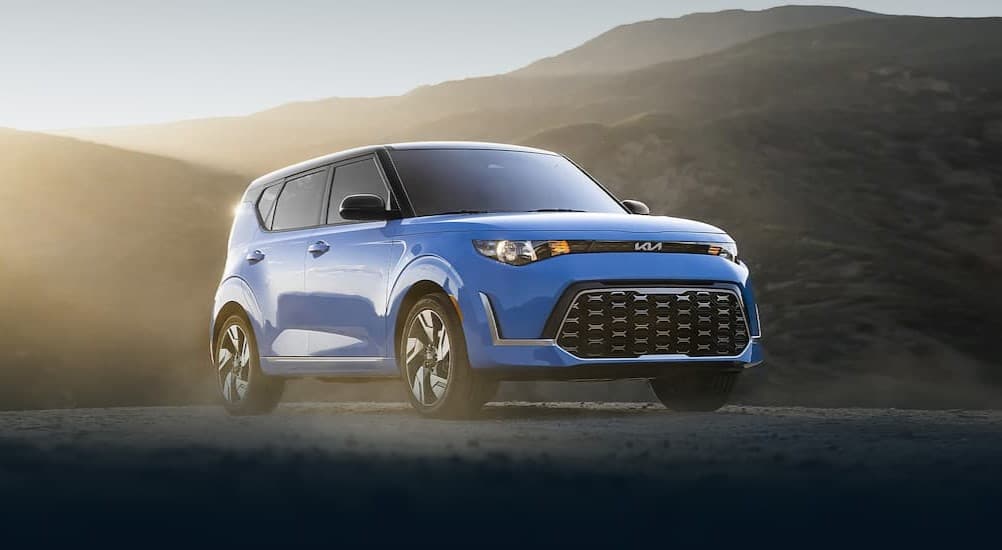 A blue 2023 Kia Sou; driving om a street.