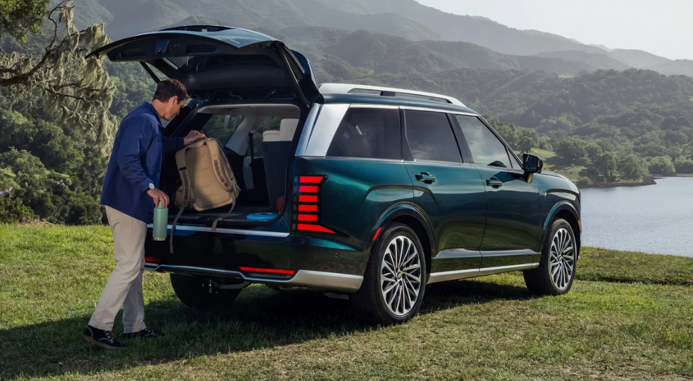 A person putting their belongings into the trunk of a green 2026 Hyundai Palisade