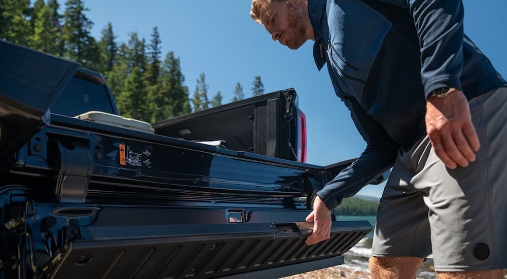 A person opening the tailgate on a black 2026 GMC Sierra 1500 for sale.