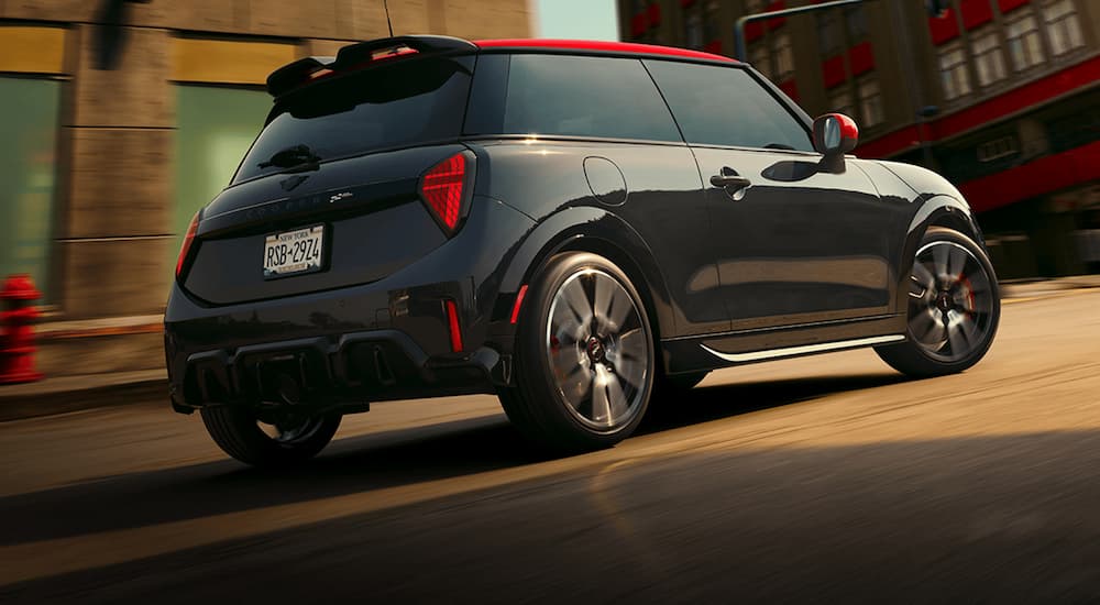 A black 2026 MINI Cooper JCW driving in a city