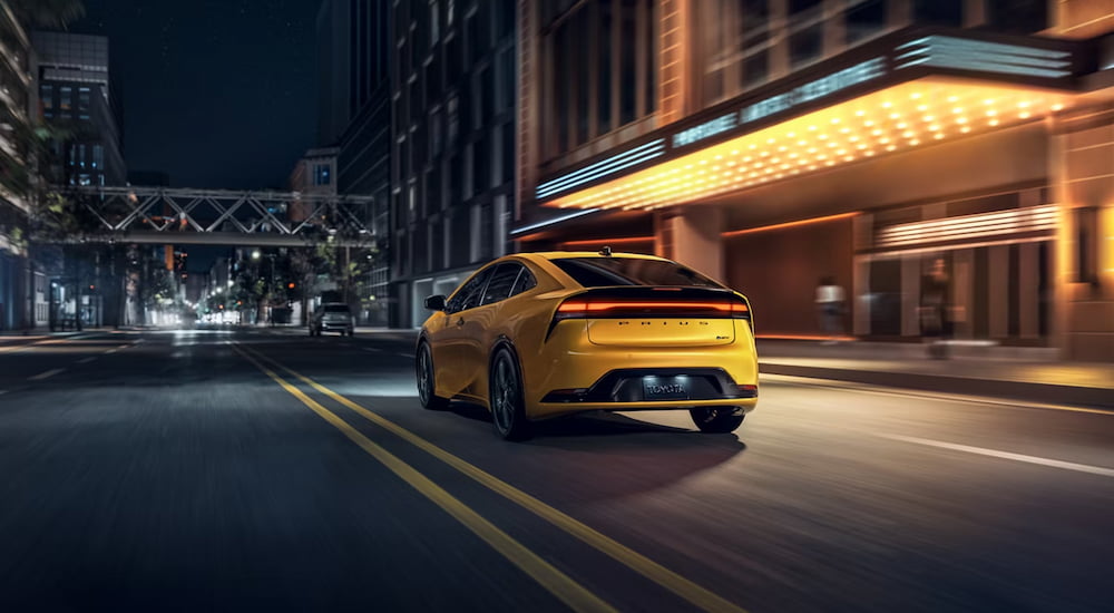 Rear of a yellow 2026 Toyota Prius driving down a road.