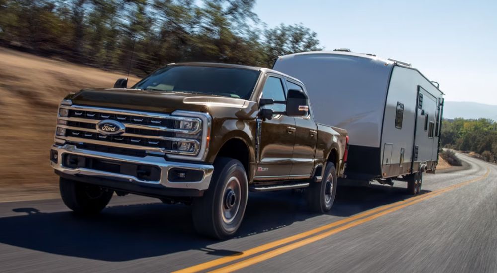 Brown 2026 Ford F-250 driving down the road with a trailer
