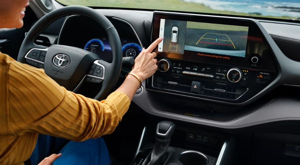 Interior view of a person using surround view monitor in a 2027 Toyota Highlander Hybrid Limited.