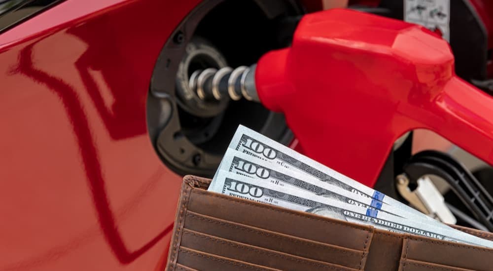 A person holding an open wallet while pumping gas.