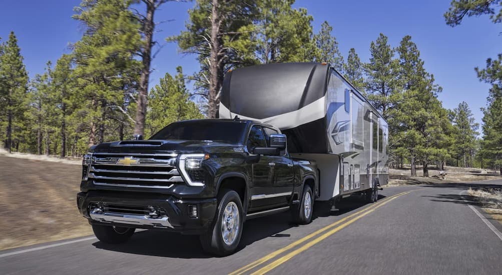 A black 2026 Chevy Silverado 3500 HD towing a trailer.