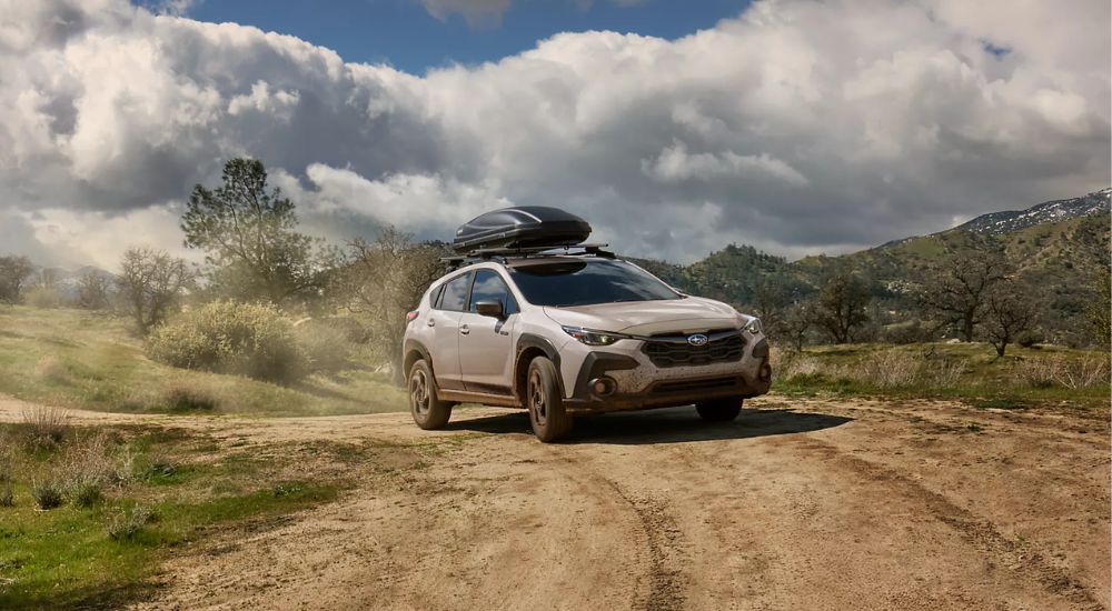 A white 2026 Subaru Crosstrek Limited Hybrid driving a dirt road.