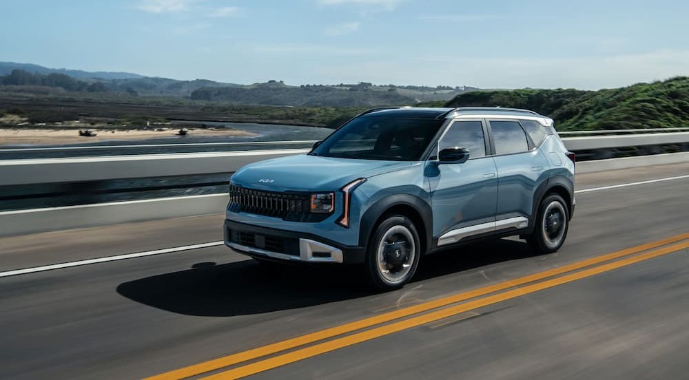 A blue 2027 Kia Seltos Hybrid driving on a highway.