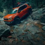 An orange 2026 Honda Passport TrailSport is shown off-roading.